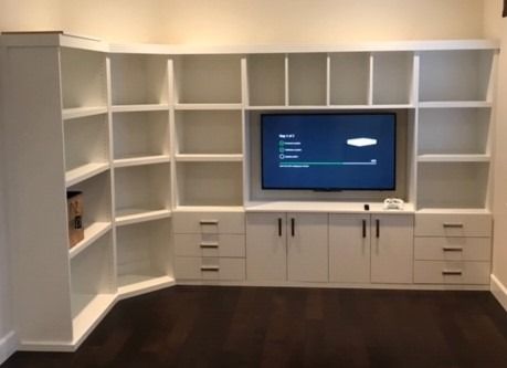 A living room with white shelves and a flat screen tv
