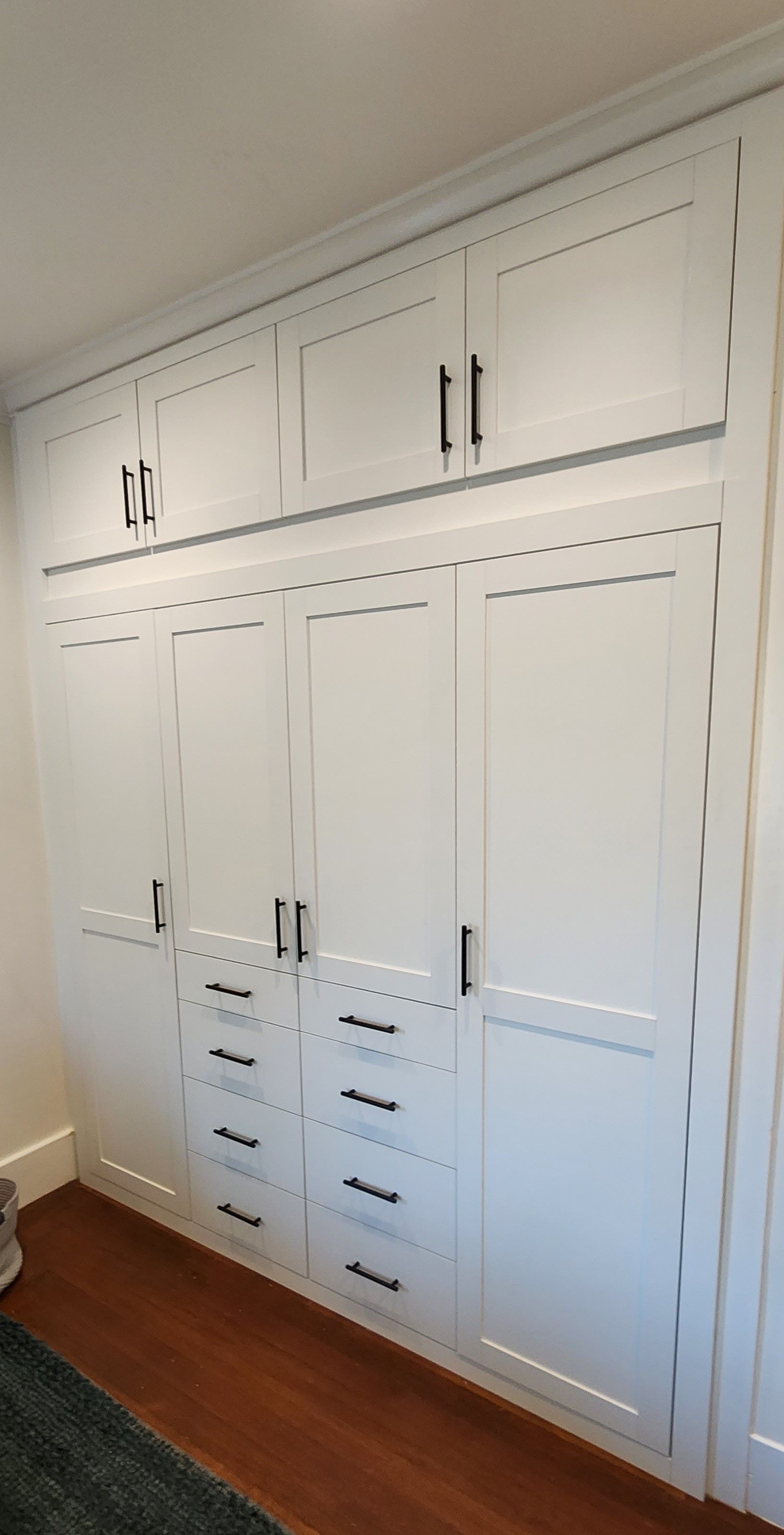 A room with a lot of white cabinets and drawers on the wall.