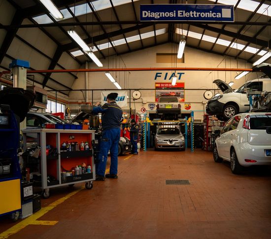 Un uomo sta lavorando su un'auto in un garage con un cartello che dice fiat