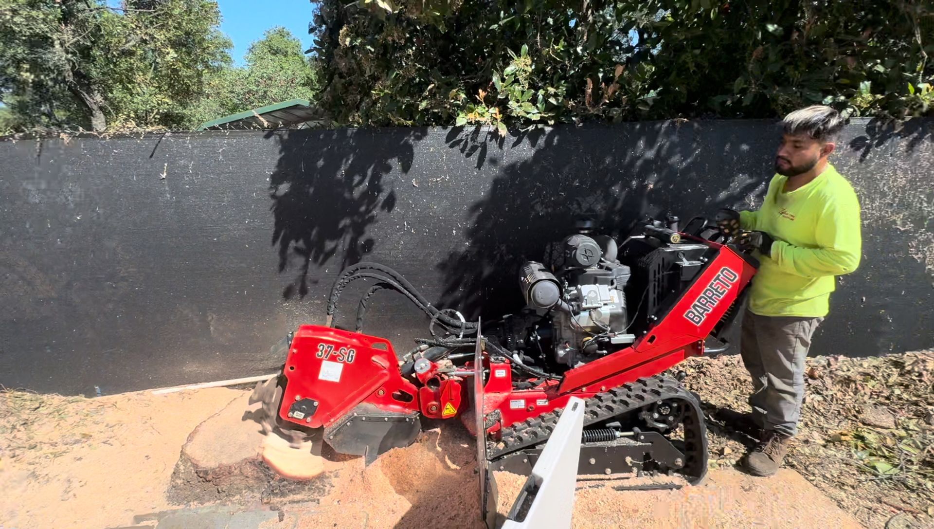 A man is using a machine to remove a tree stump.