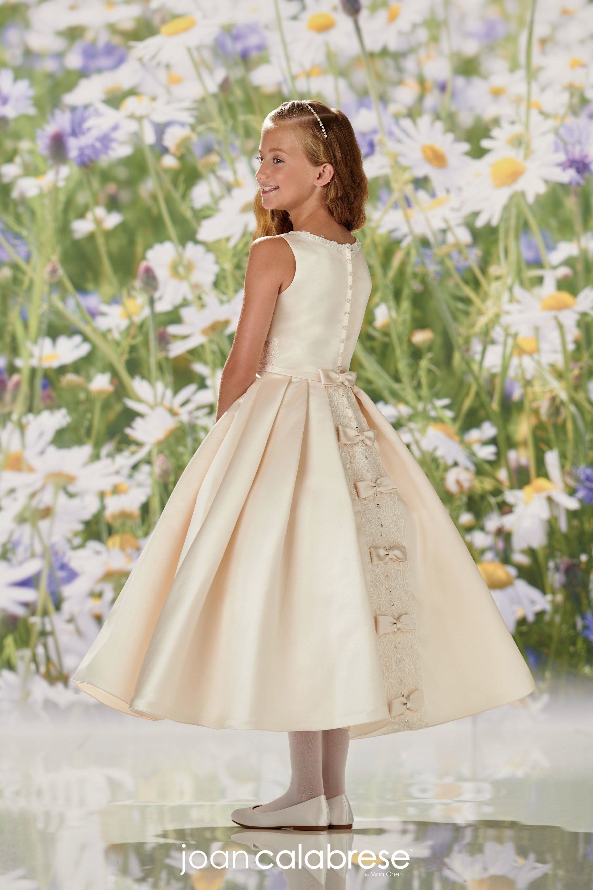 Girl in a cream dress posing in front of a floral backdrop