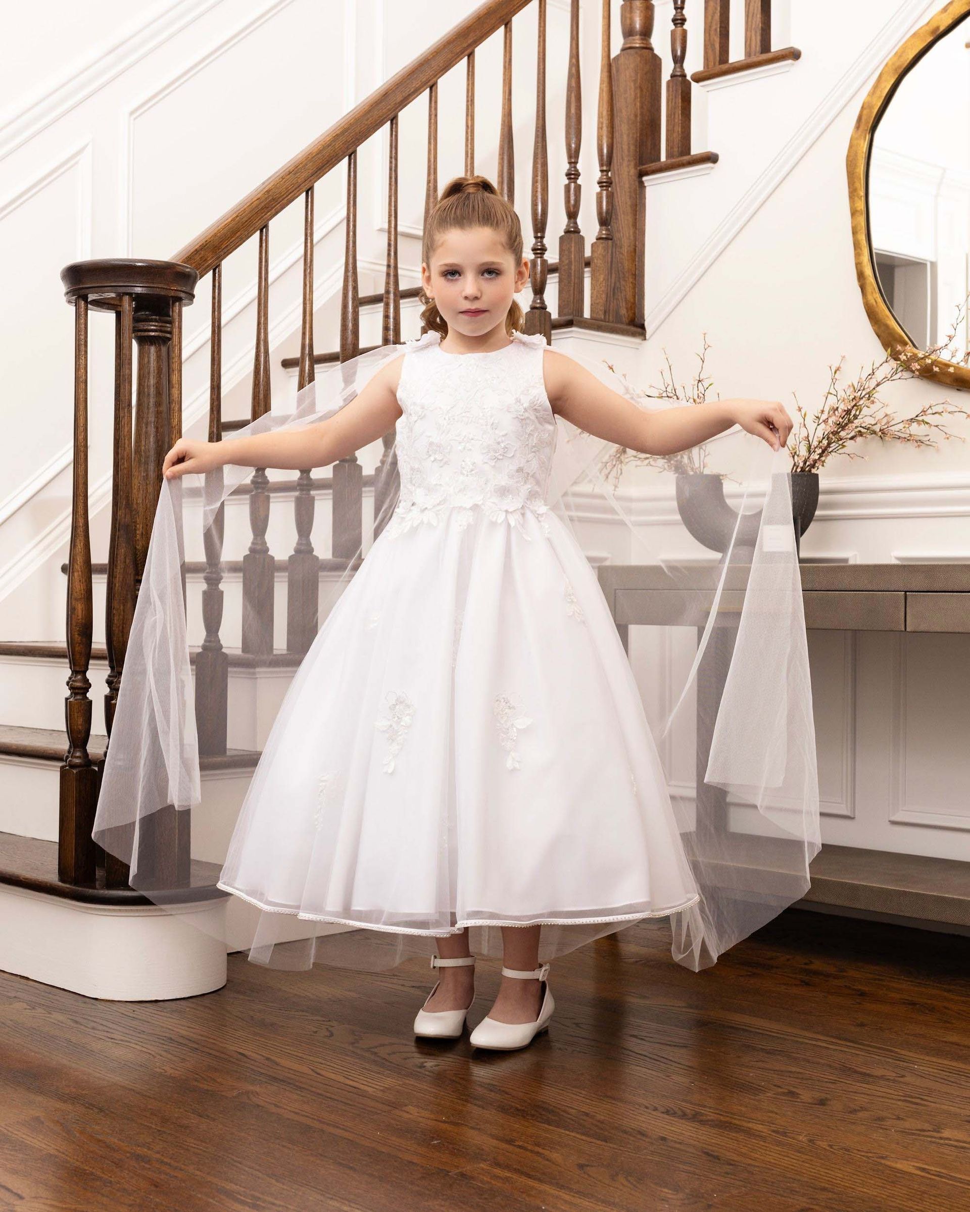 Young girl in a white dress posing on a staircase in a bright room