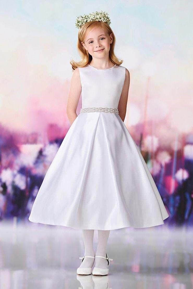 Child in a white dress and floral headband, standing against a soft pink and purple background.