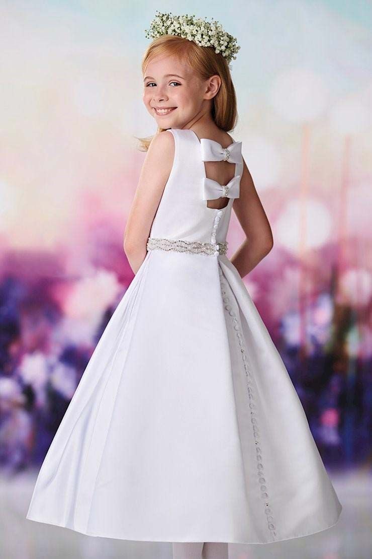 Young girl in a white dress smiling over her shoulder against a soft pastel background