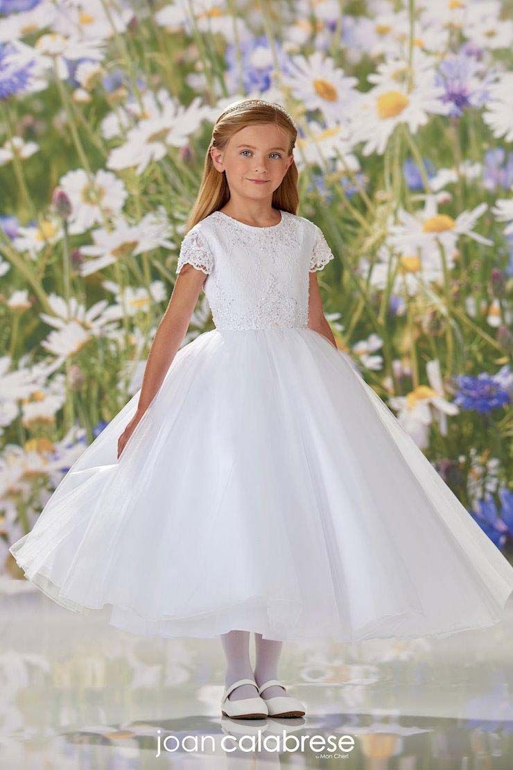 Young girl in a white dress standing against a floral garden backdrop