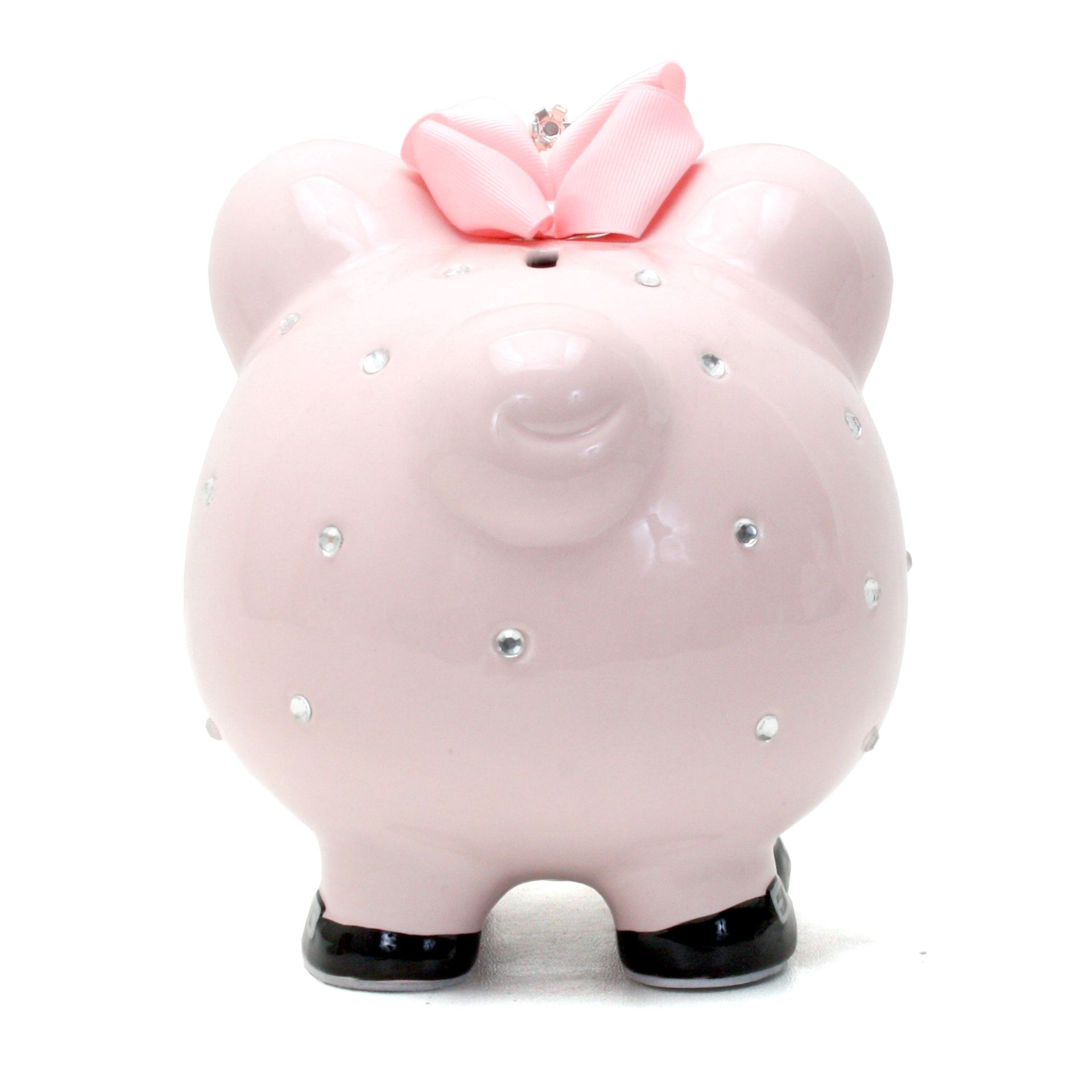 Pink piggy bank with rhinestone accents and a pink bow on top, standing on black feet.