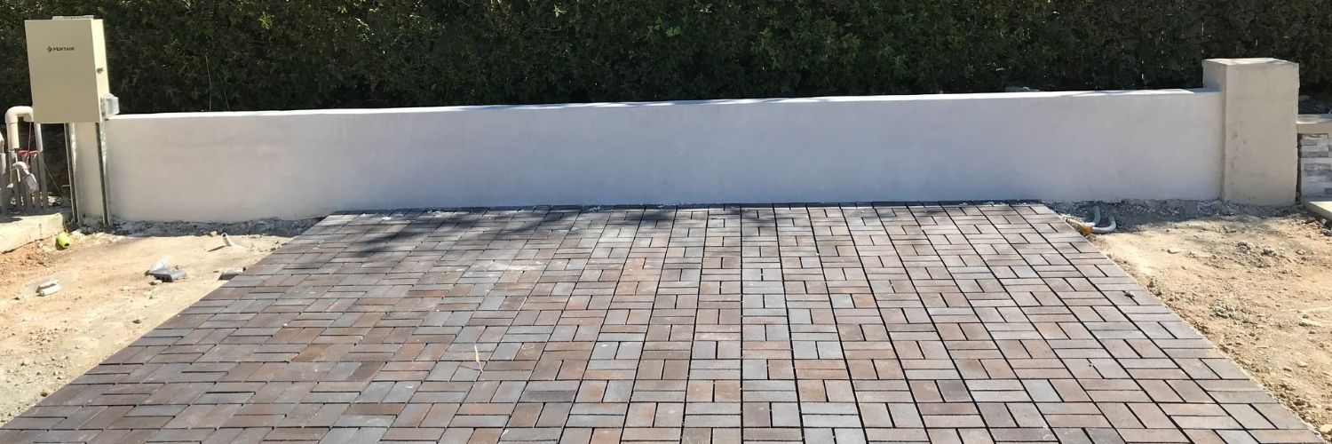 A brick driveway with a white wall in the background.