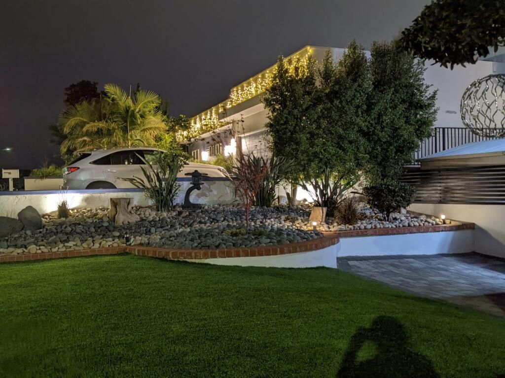 Nighttime landscape with lit building, landscaped garden, and parked car at a modern property