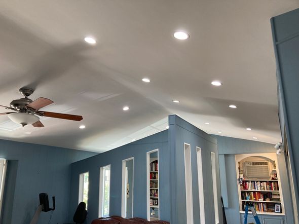 Bright living room with blue walls, recessed lights, ceiling fan, and bookshelves in the background