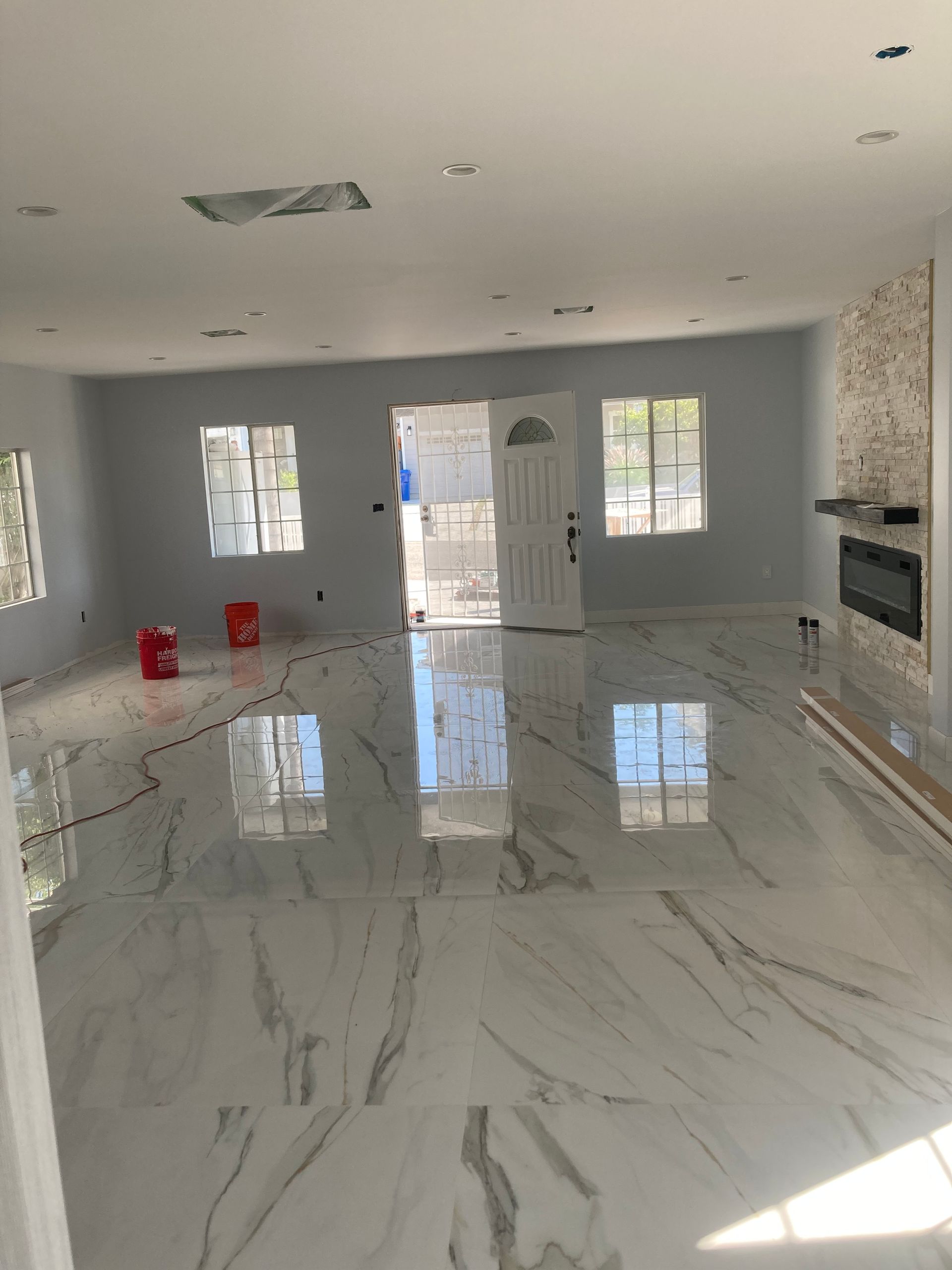 Empty modern living room with glossy white marble floor and bright natural light from windows.