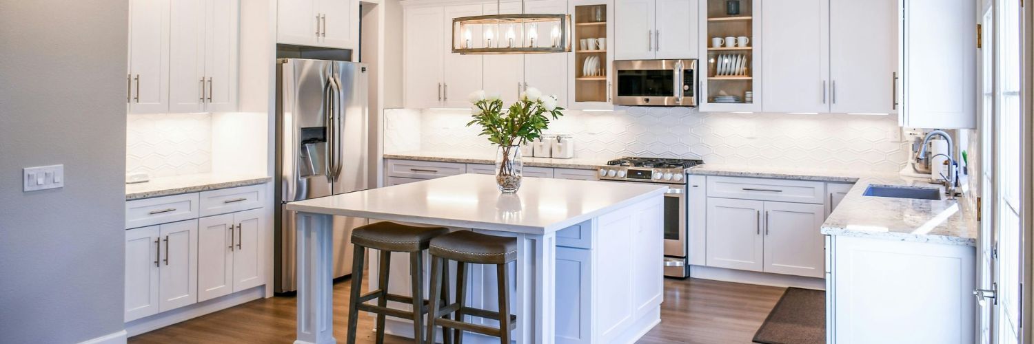 Bright modern kitchen with white cabinets, stainless steel appliances, and a central island with stools