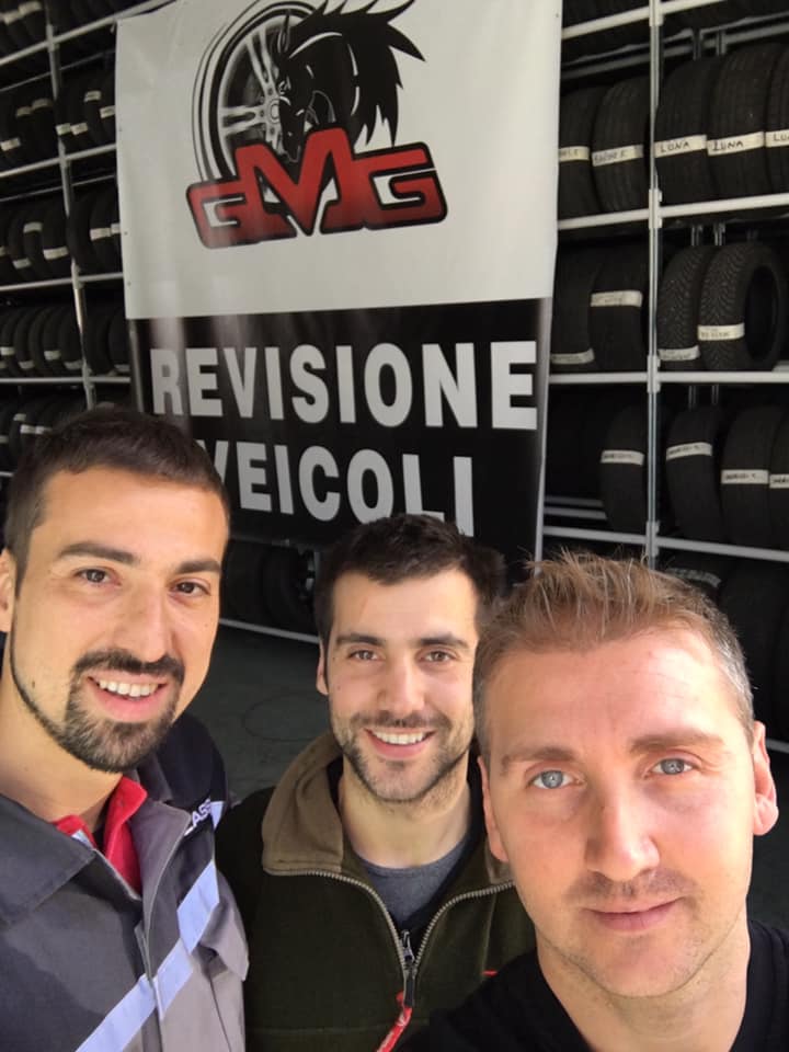 Tre uomini sorridenti davanti a un cartello con la scritta 