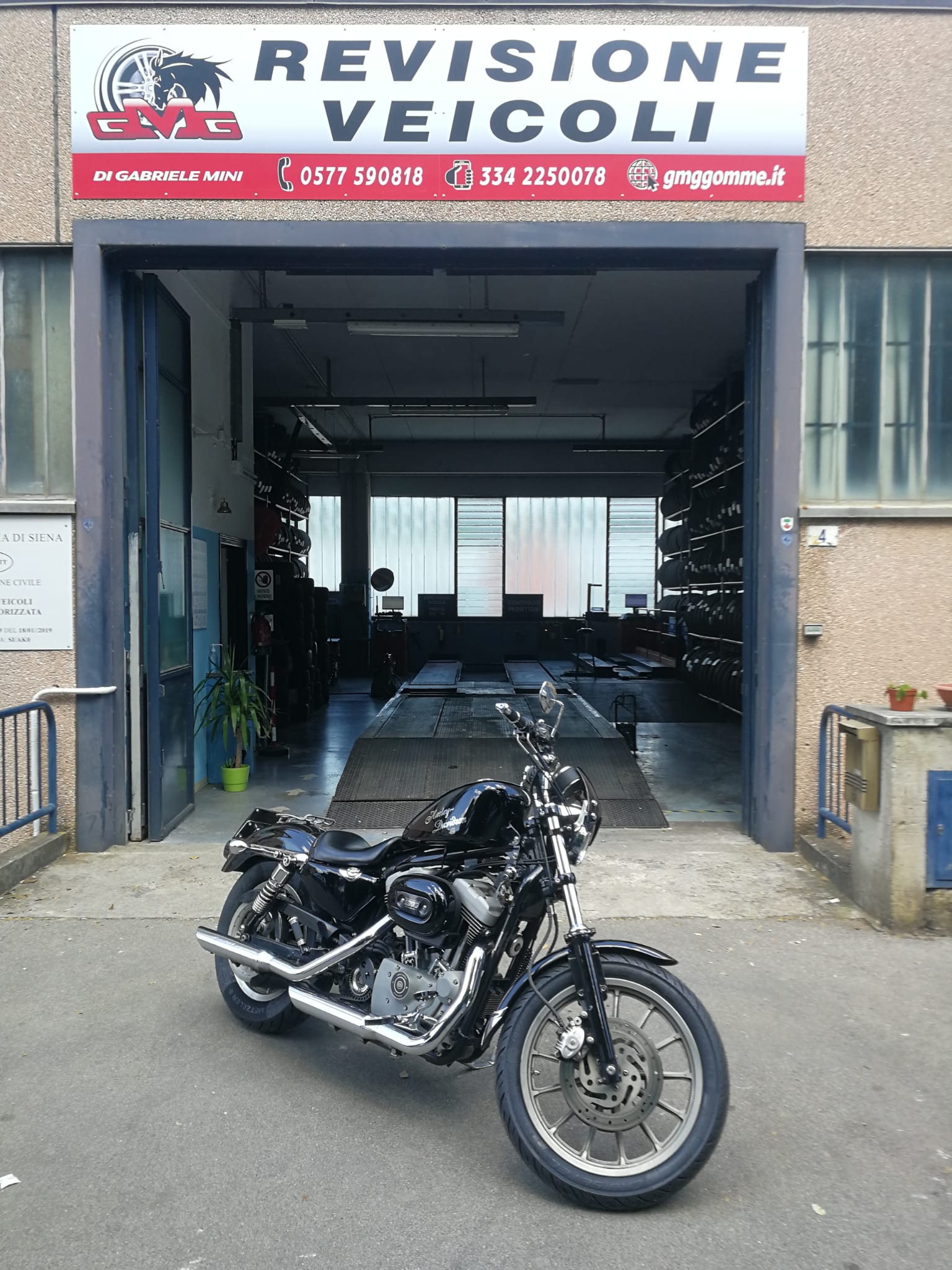 Motocicletta nera parcheggiata davanti a un'officina di revisione veicoli.