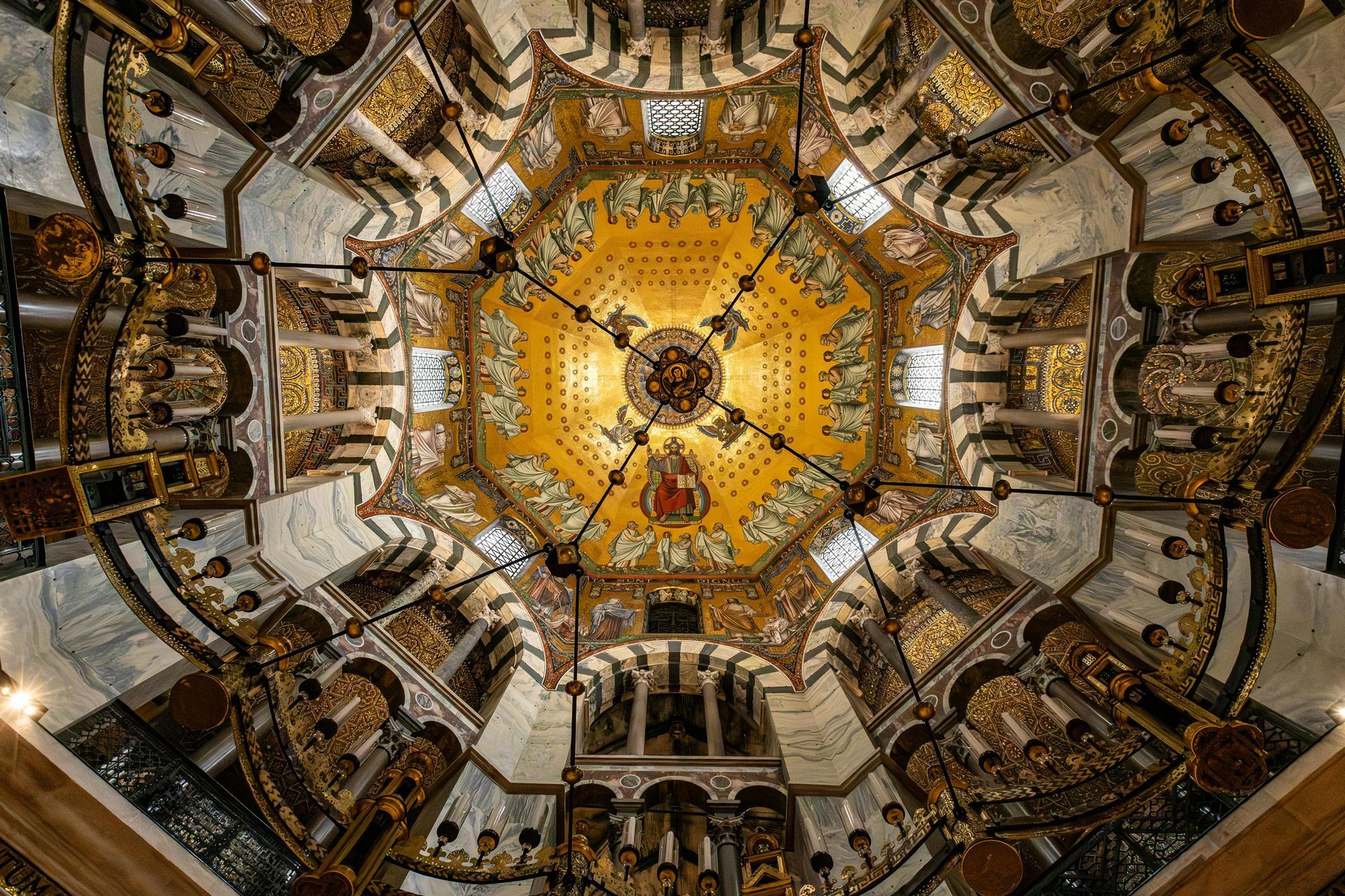 Soffitto a cupola di cattedrale riccamente decorato con mosaici dorati e archi elaborati, visto dal basso.
