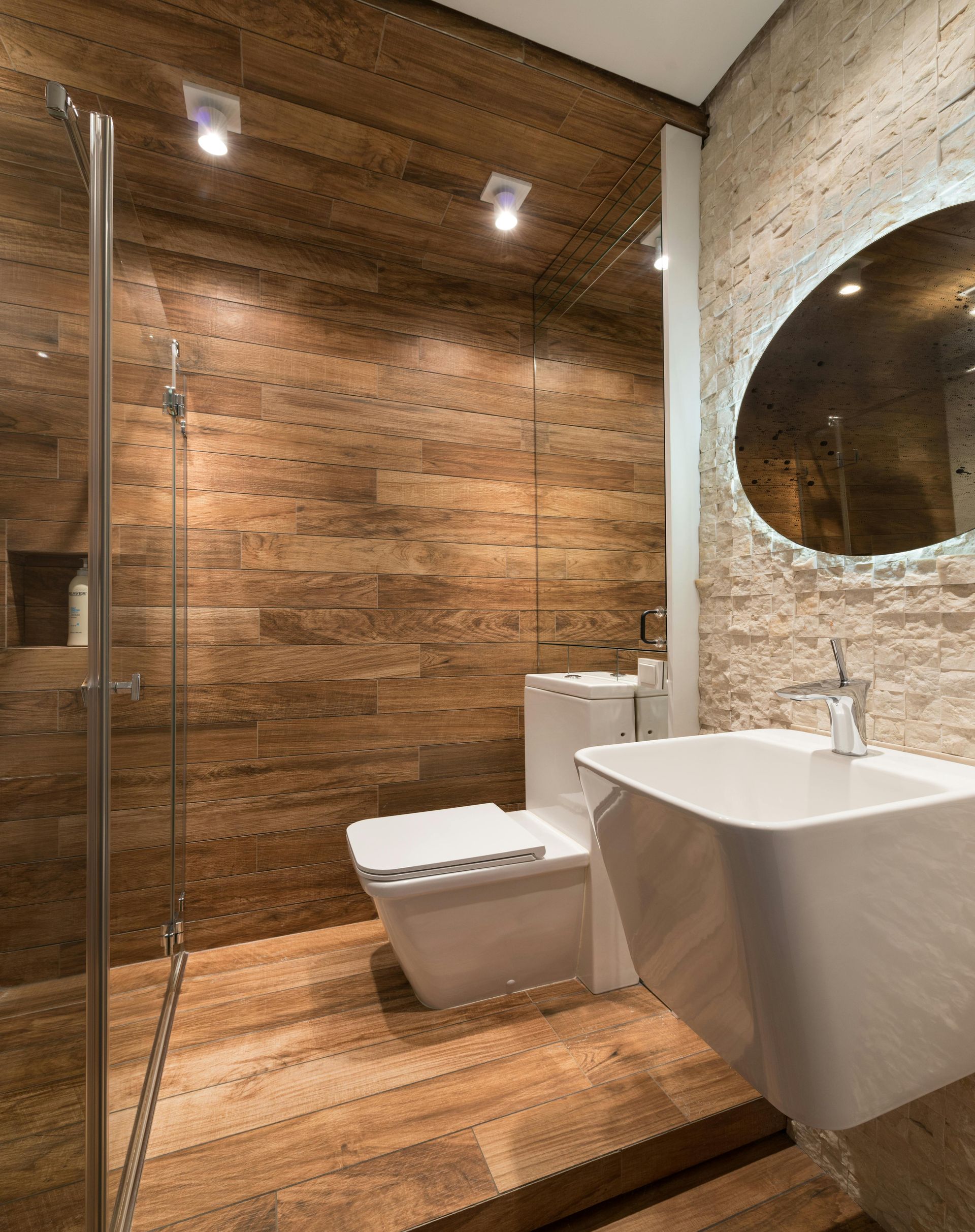 A bathroom with a toilet , sink , shower and mirror.