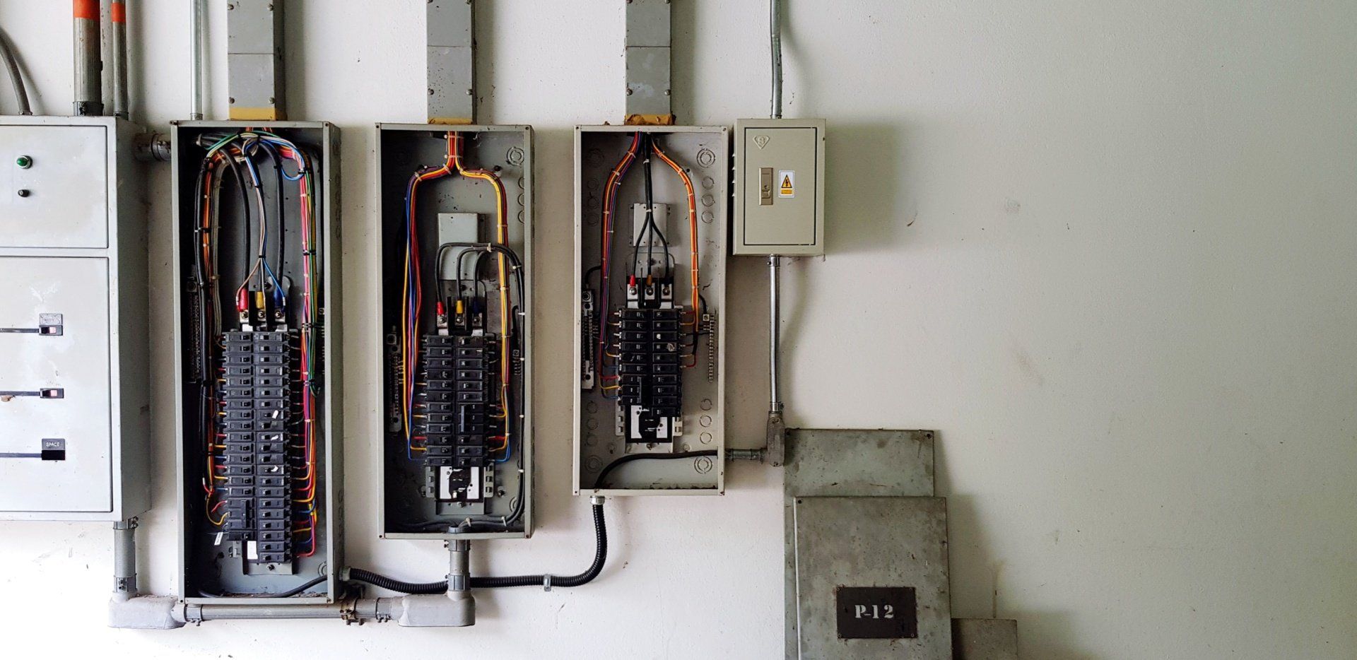 Three electrical boxes are lined up on a white wall