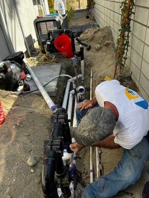 A man is working on a pipe in the dirt.