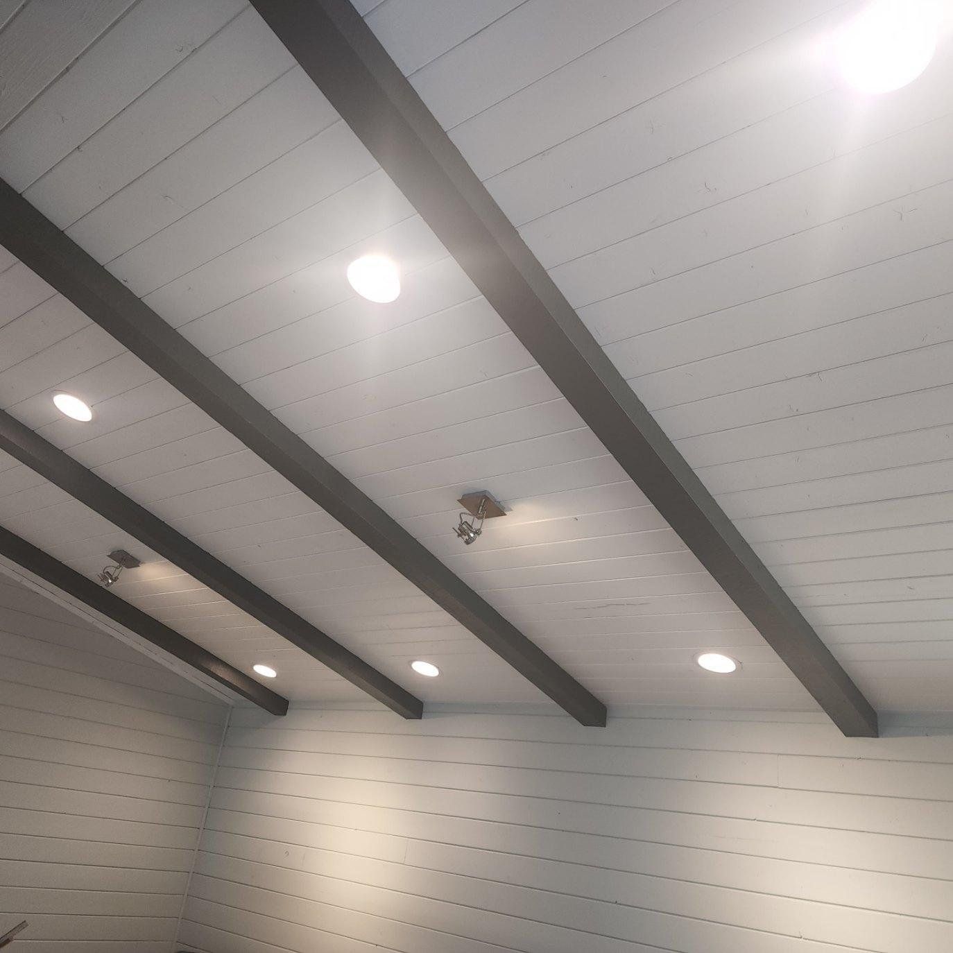 A room with a white ceiling and black beams.