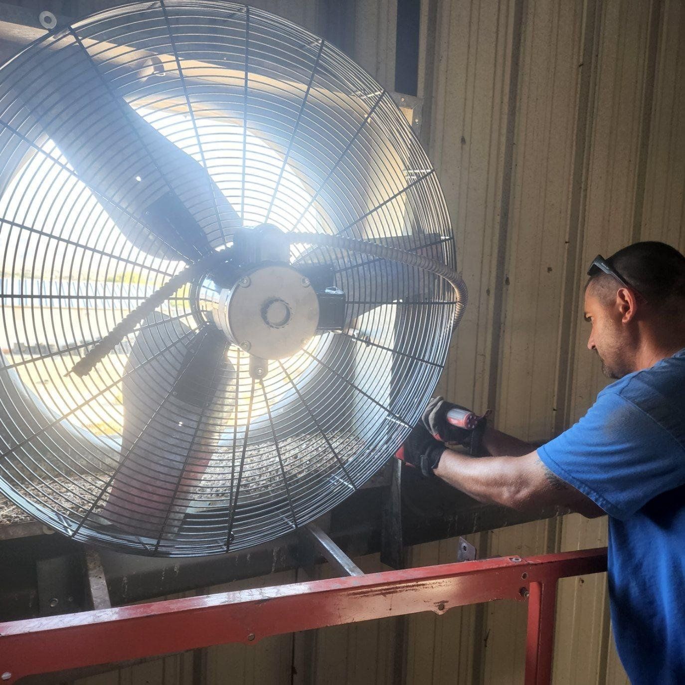 A man is working on a large fan in a building.