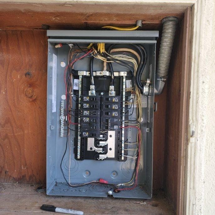 A electrical panel is sitting inside of a wooden box.