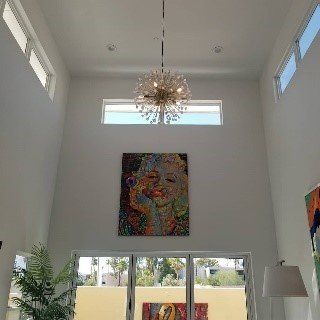 A living room with a painting on the wall and a chandelier hanging from the ceiling