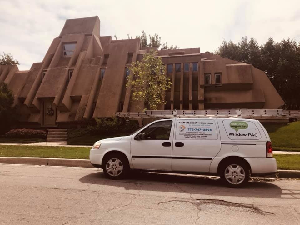 A white van is parked in front of a large building