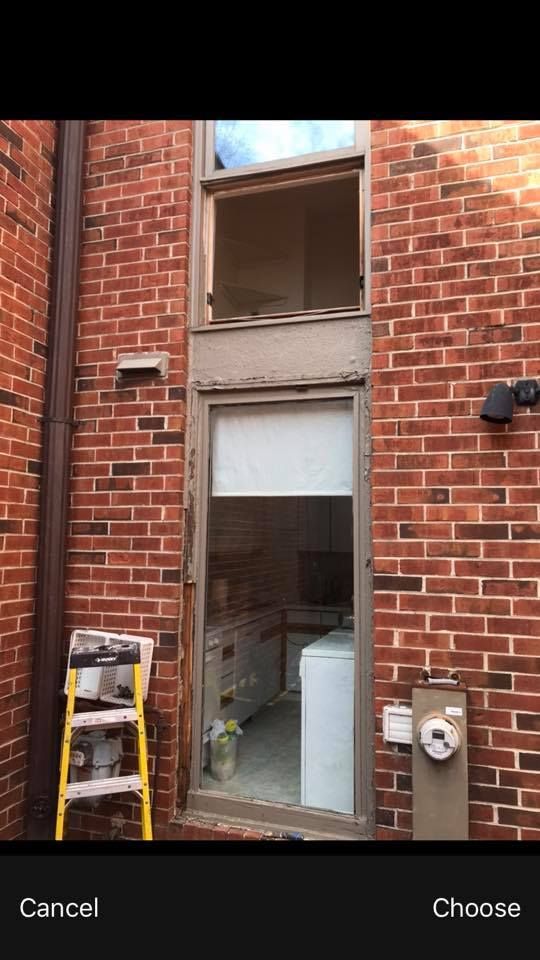 A ladder is sitting on the side of a brick building next to a window.
