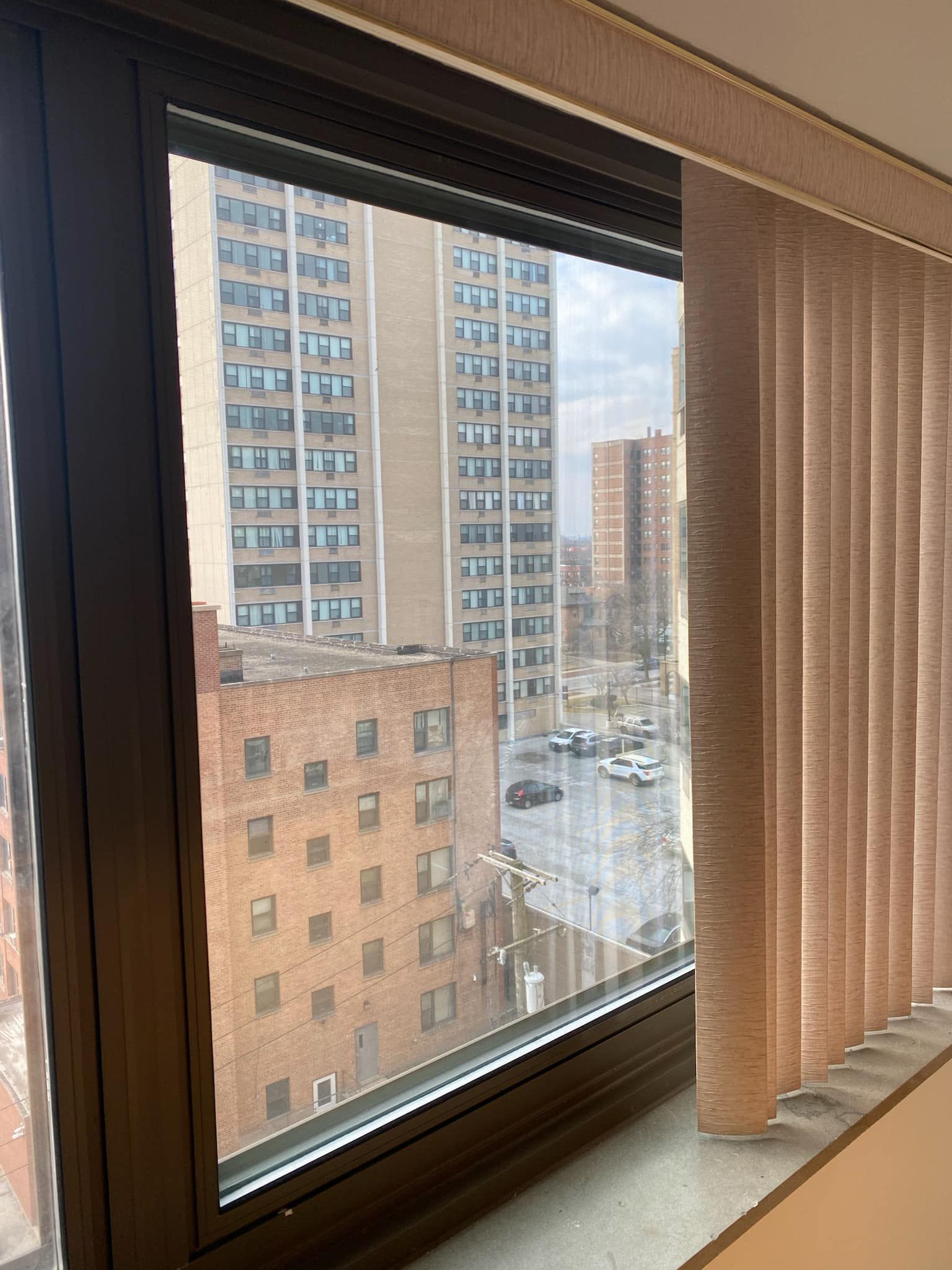 A window with vertical blinds and a view of a city.