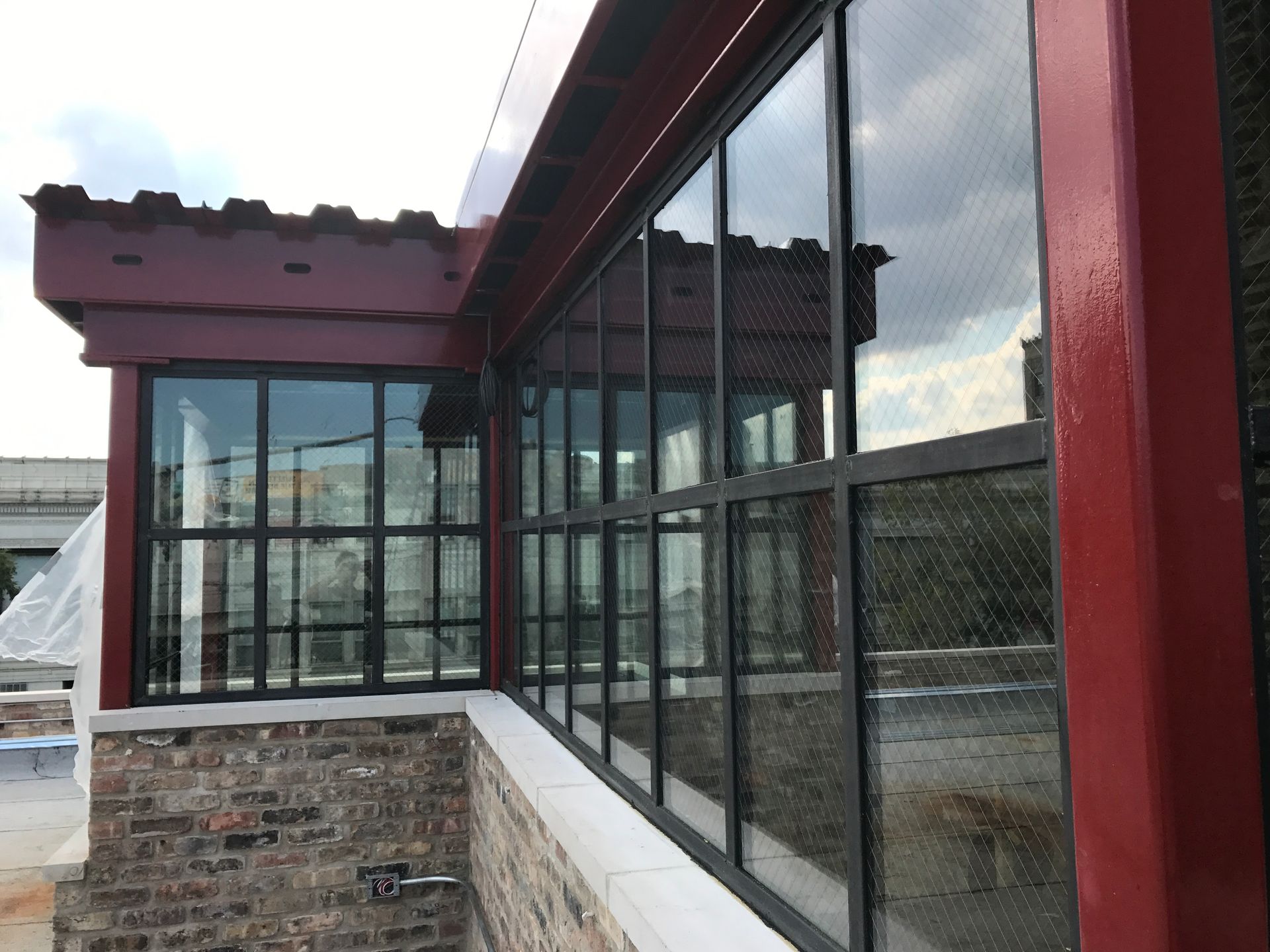 Exterior view: brick building with black-framed windows and a red support beam.