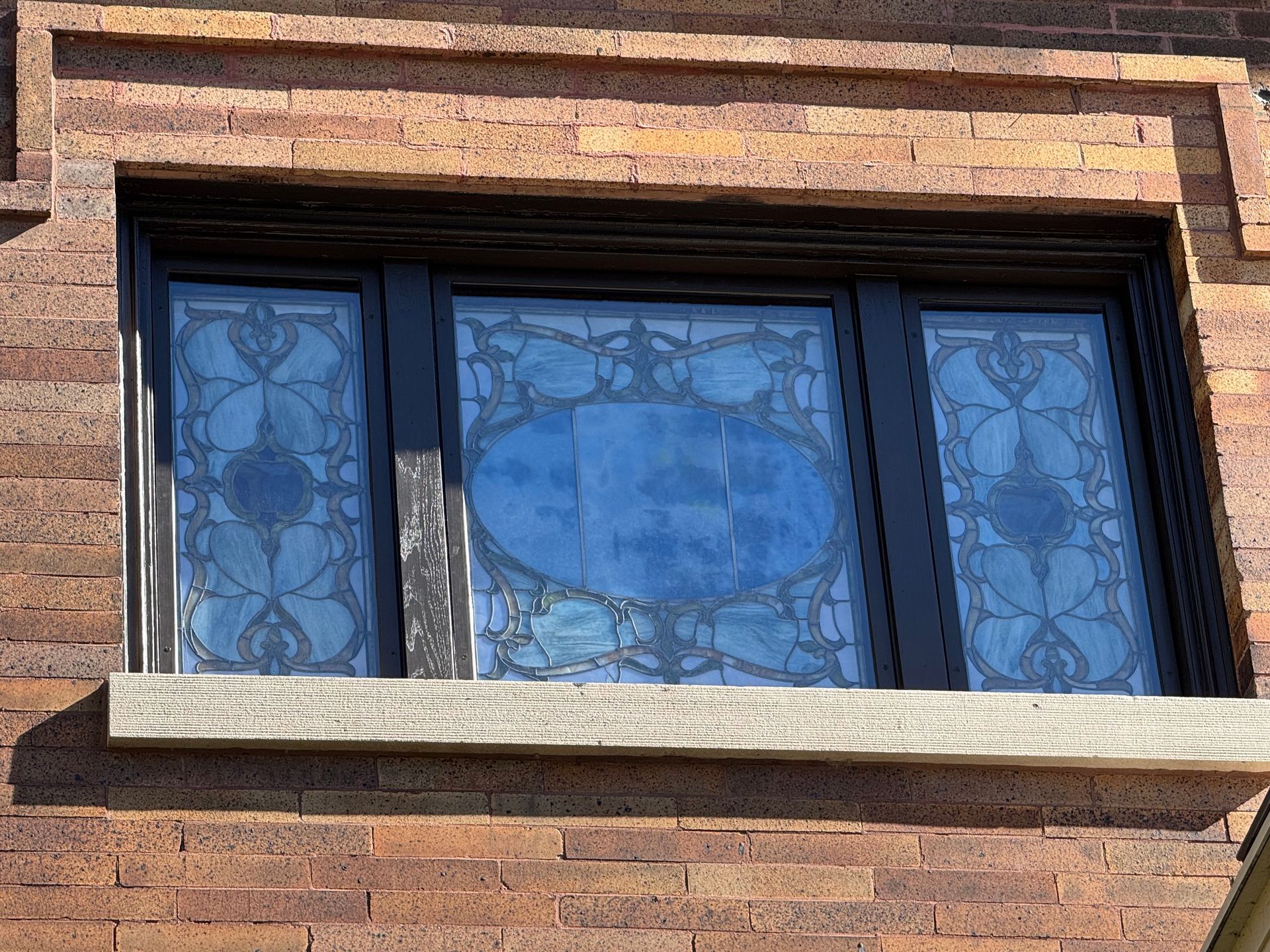 A brick building with three windows and a stained glass window