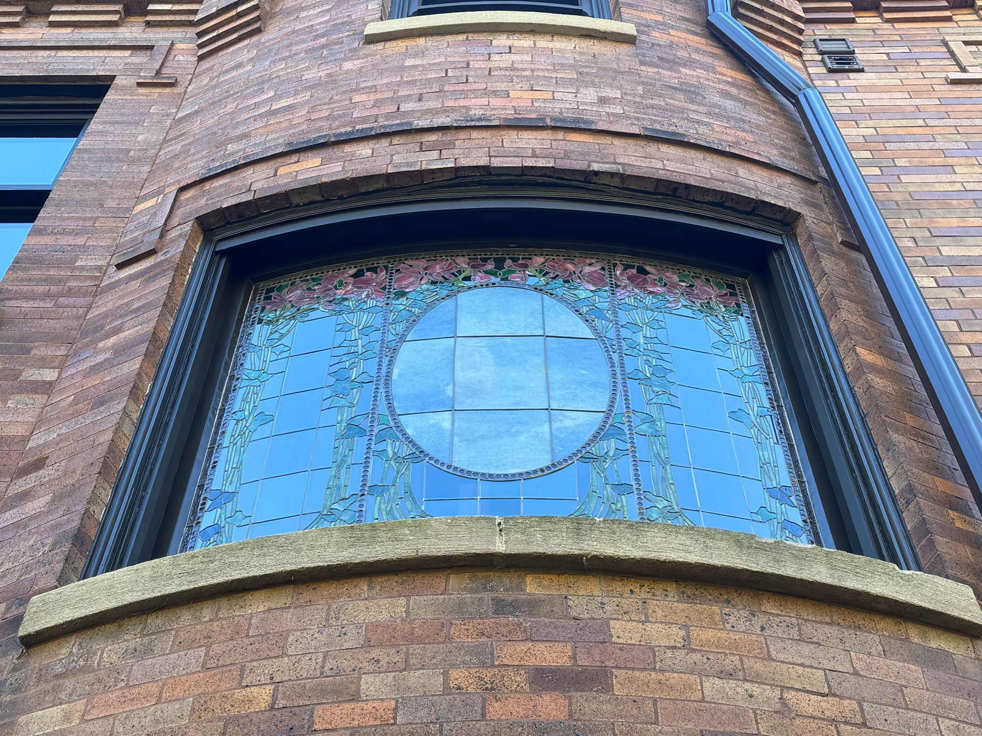 Brick building with a large arched stained-glass window featuring a central circle and floral details.