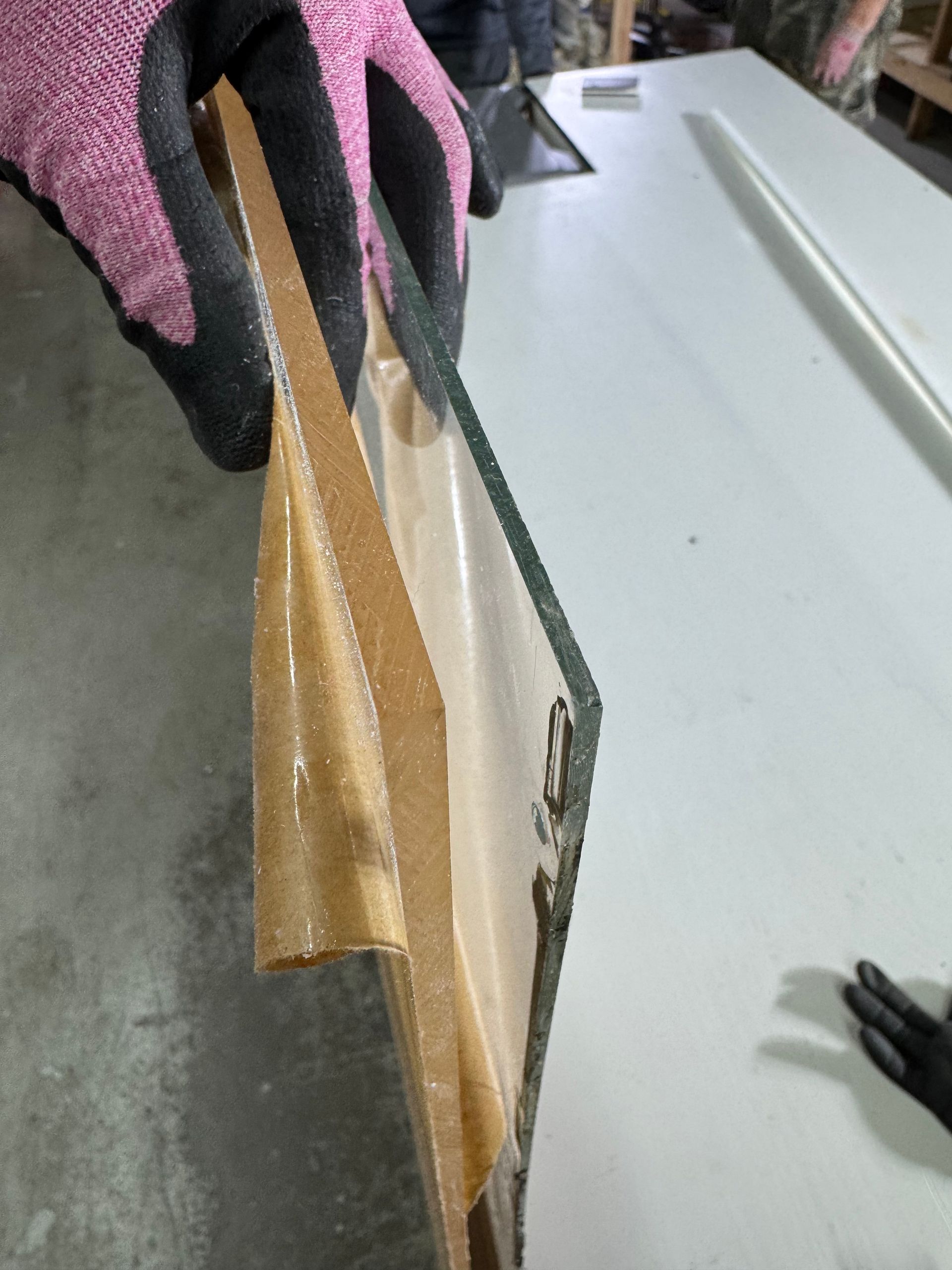 A person wearing pink gloves is holding a piece of acrylic