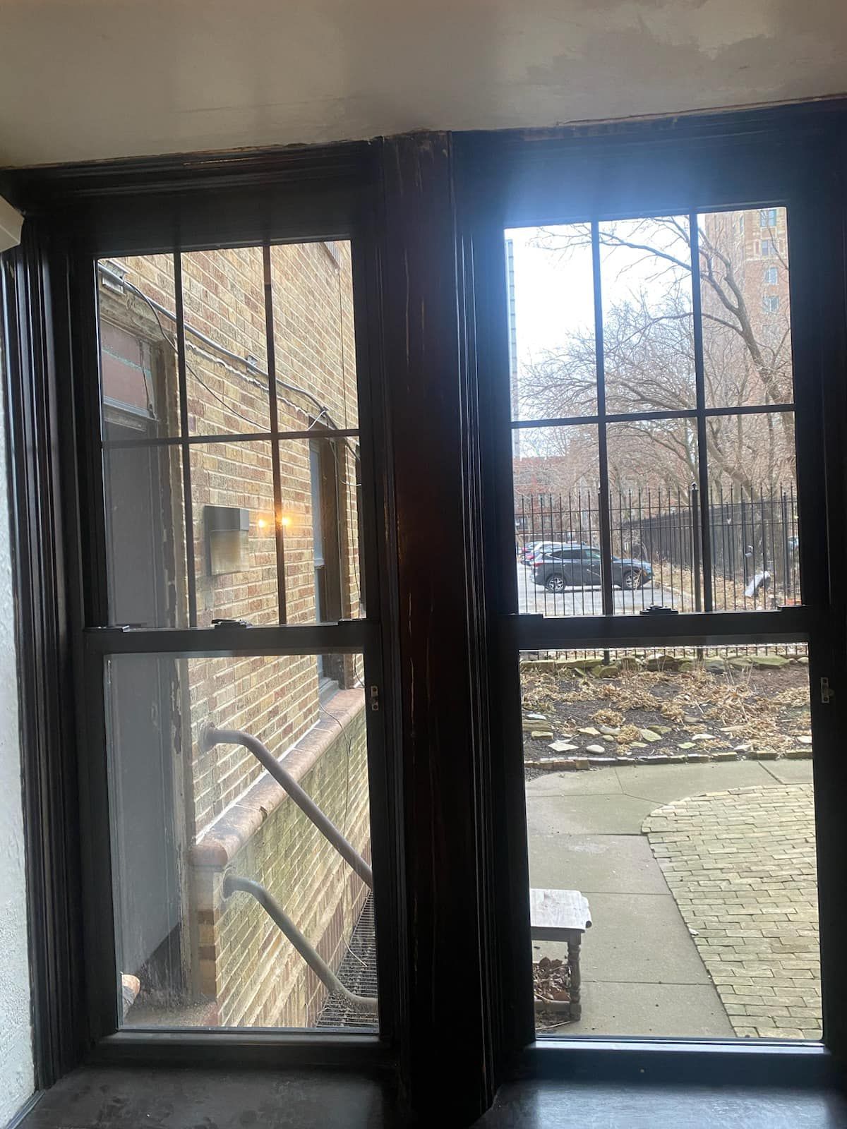 A window with a view of a brick building and a sidewalk.