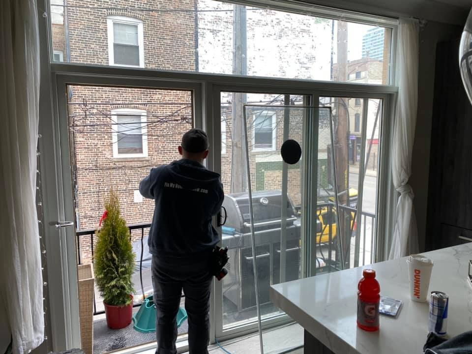A man is cleaning a window in a living room.