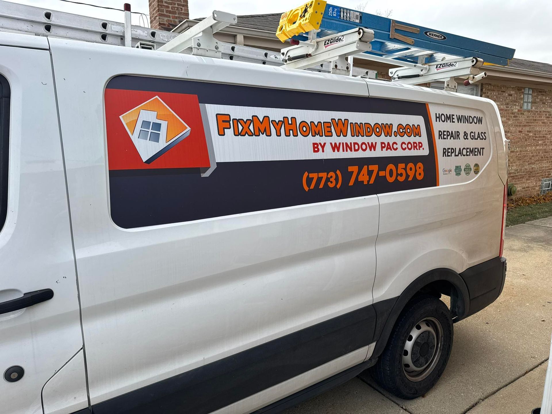 A white van with a ladder on top of it is parked in front of a house.