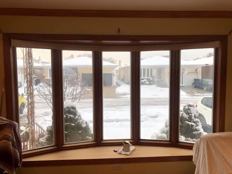 A living room with a large bay window looking out to a snowy yard.