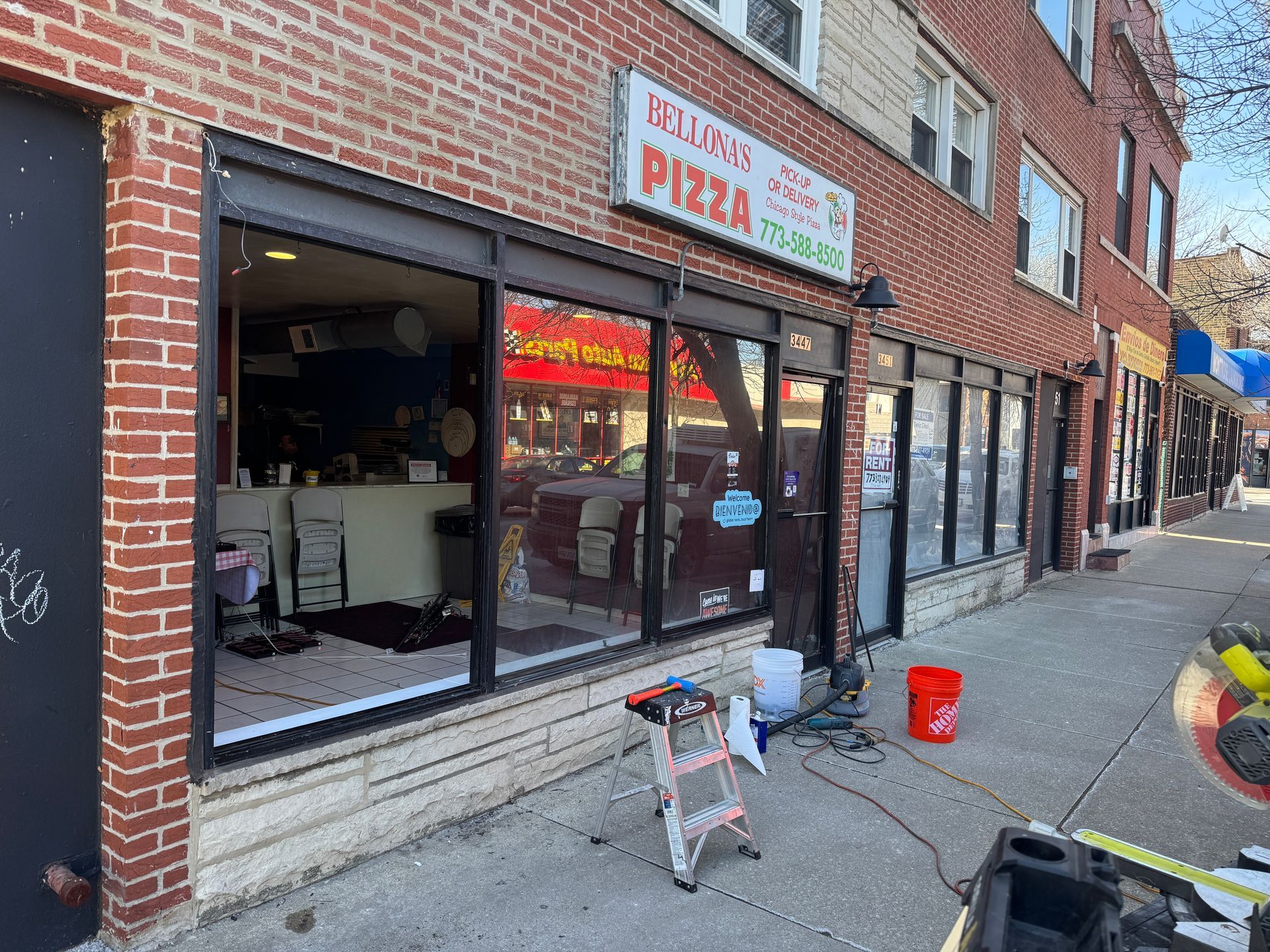A pizza restaurant is being remodeled on the side of a brick building.
