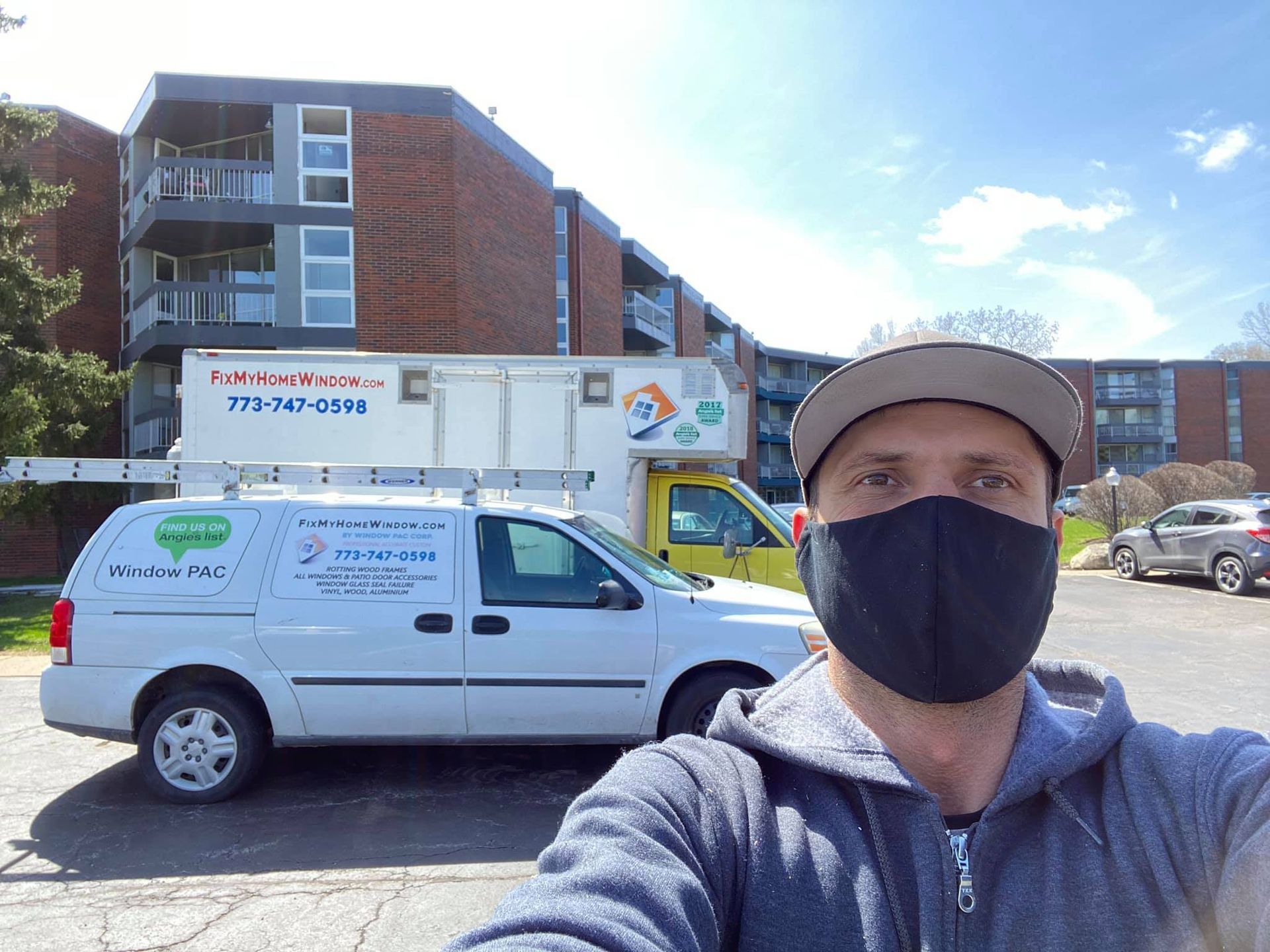 A man wearing a mask is taking a selfie in front of a van.