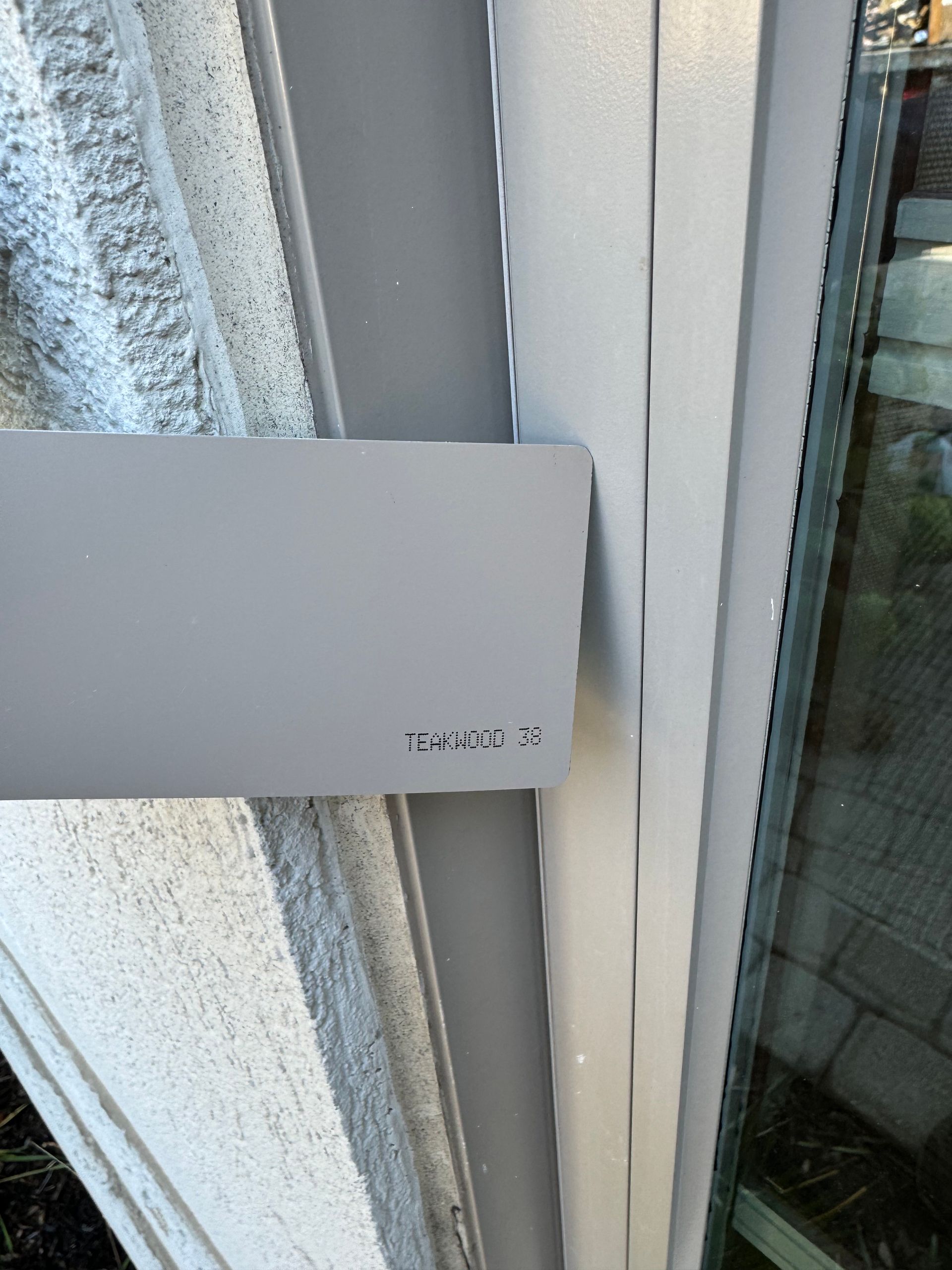 A white box is sitting on the side of a building next to a window.