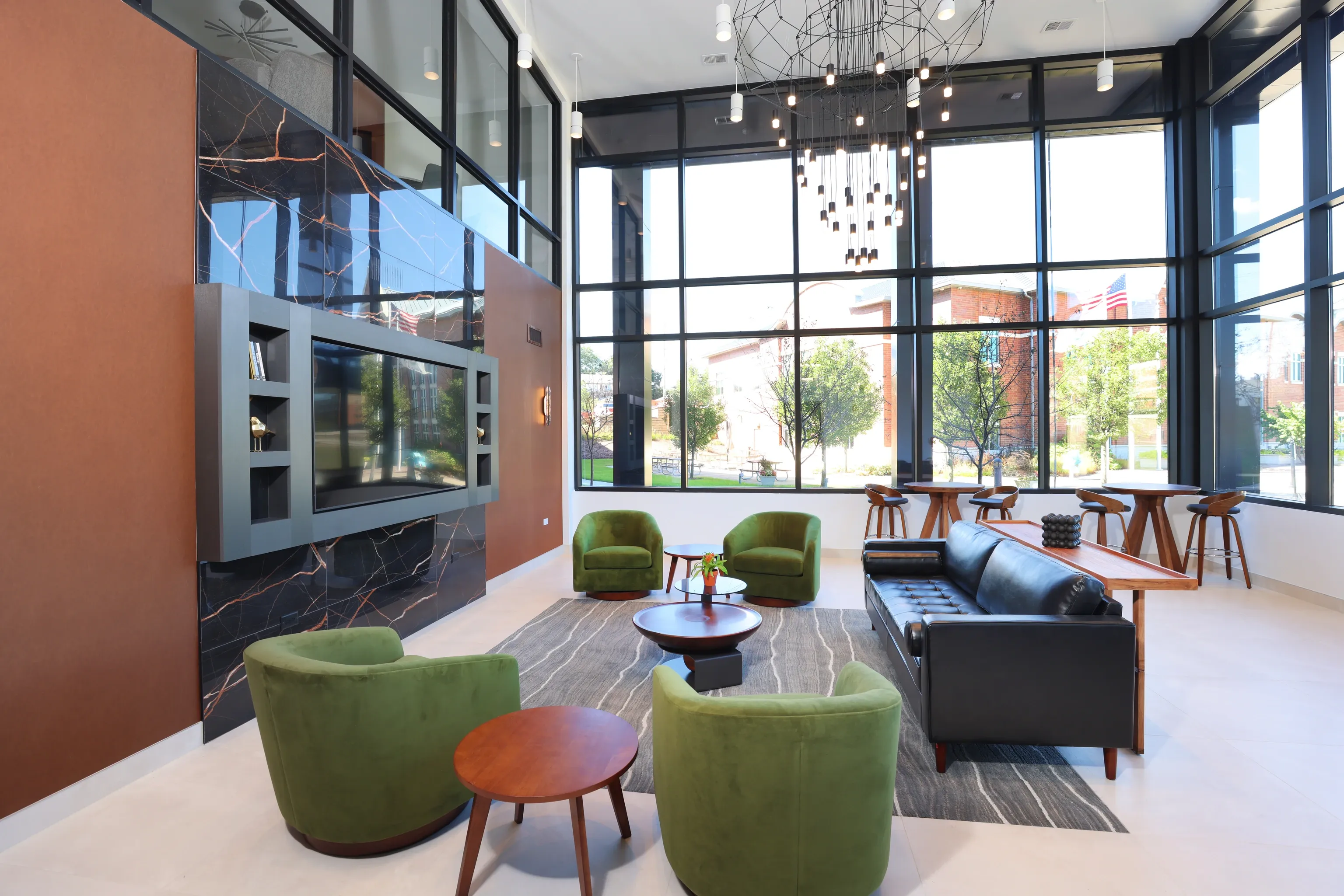 Modern lounge area with large windows, comfortable seating, and a television at Station 250 in Mundelein, IL.