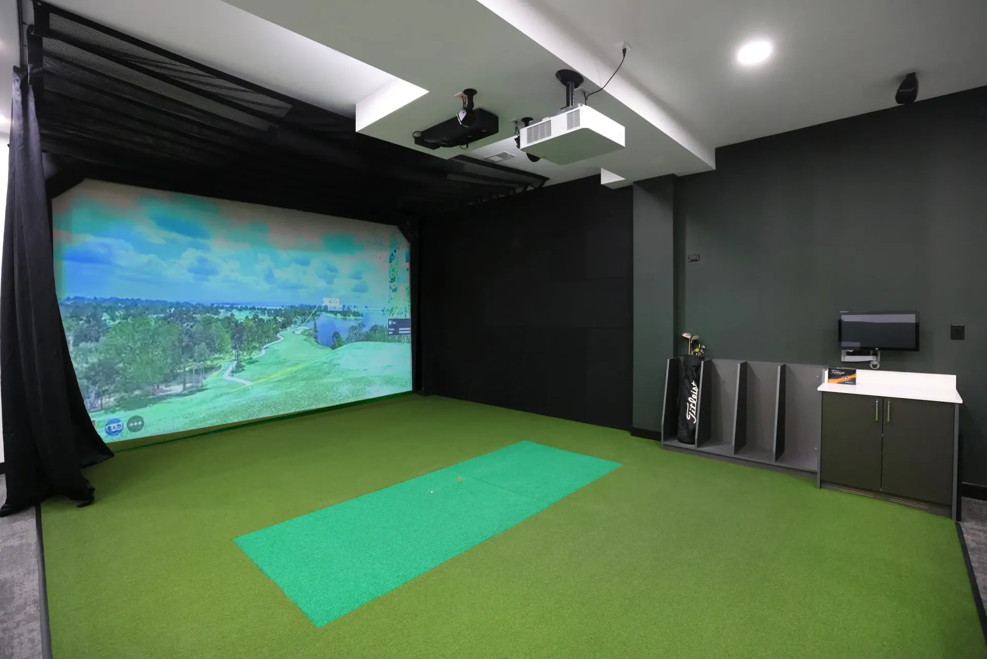 Indoor golf simulator with projector and screen displaying a golf course at Station 250 in Mundelein, IL.