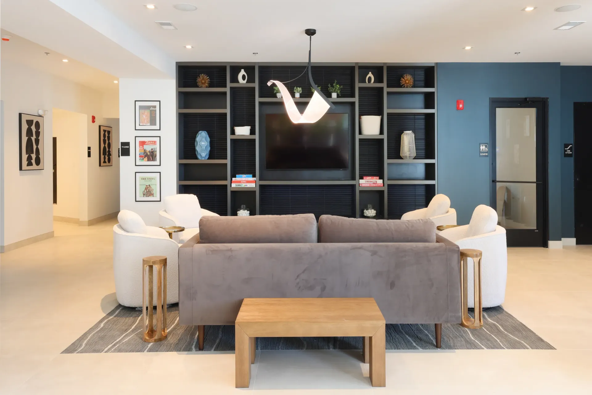 Modern communal living area with plush seating and a large media wall at Station 250 in Mundelein, IL.