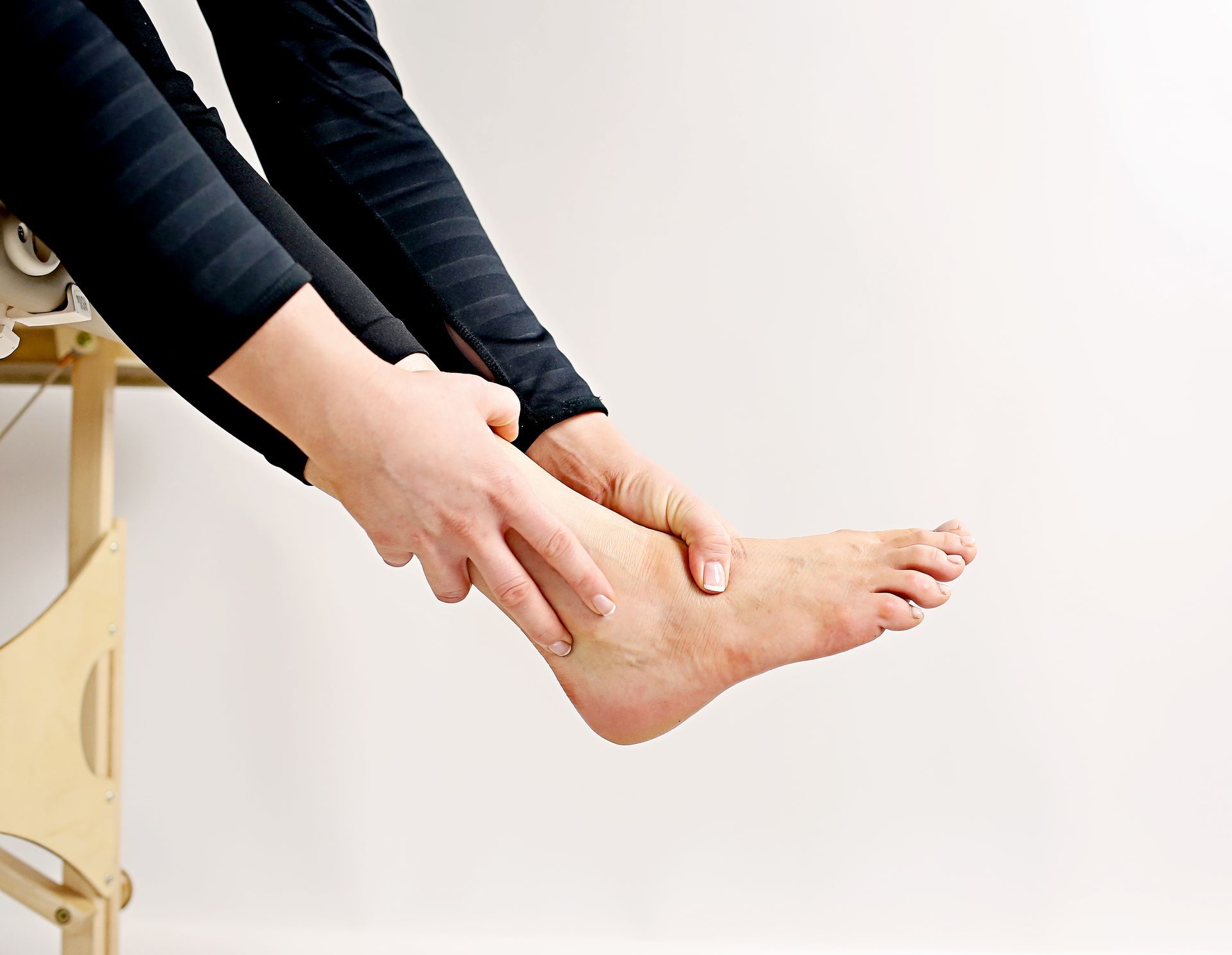 a woman is sitting on a table holding her foot.