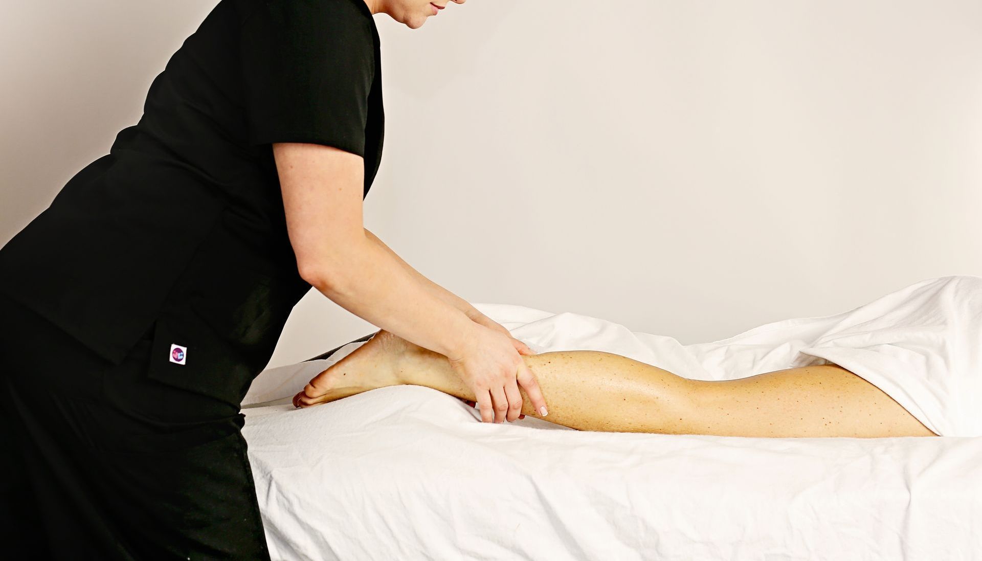A woman is giving a leg massage to a woman at A Touch of Recovery in Plymouth, MI