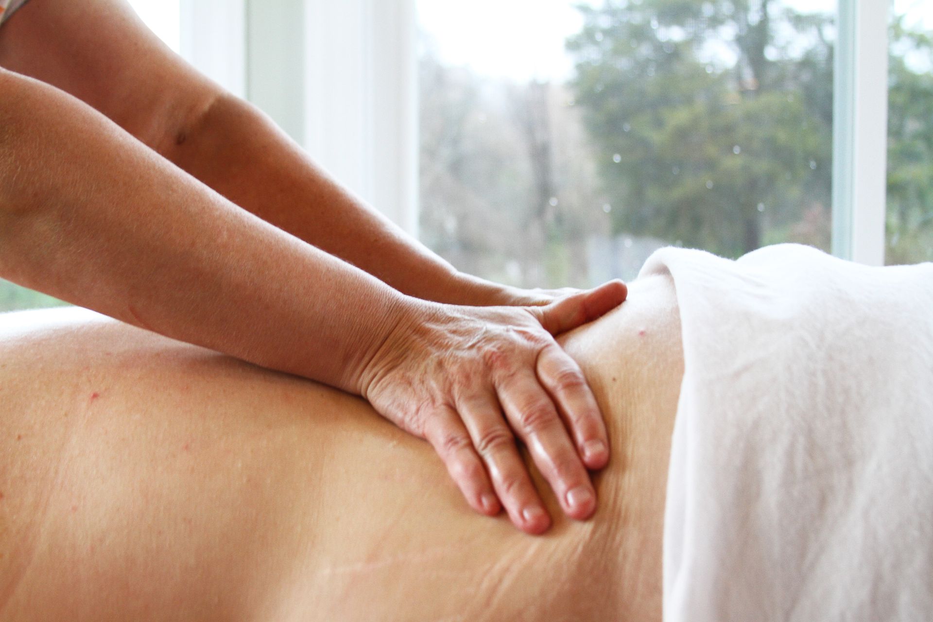 a woman is getting a massage on her back in front of a window .