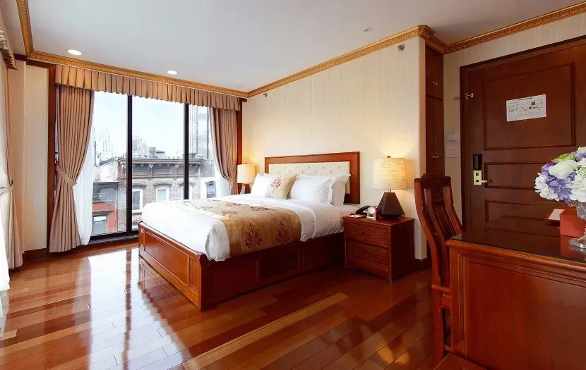 Hotel room with a large window, wooden bed, and desk.