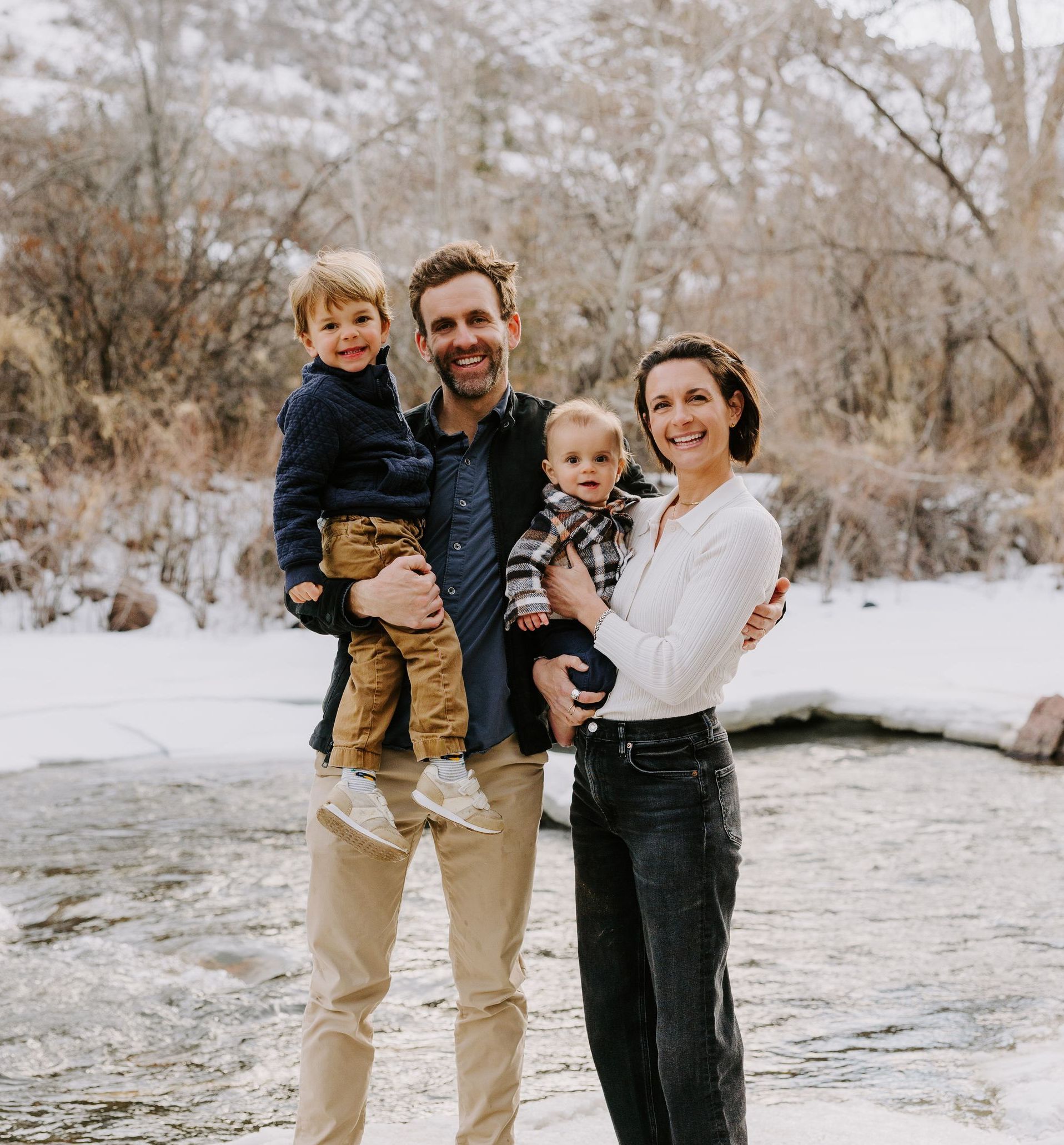 A family is posing for a picture in front of a river.
