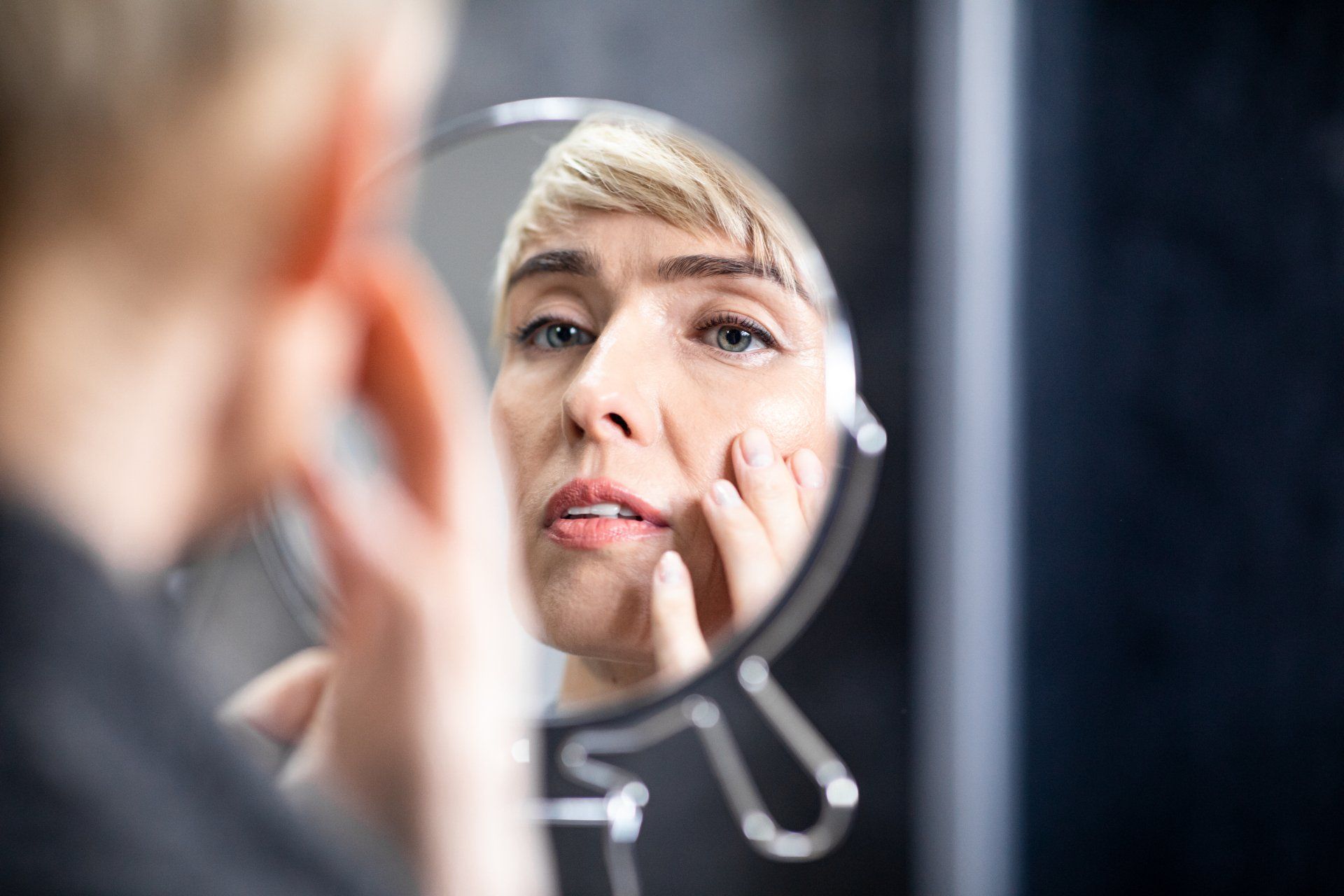 Woman looking at her skin in the mirror