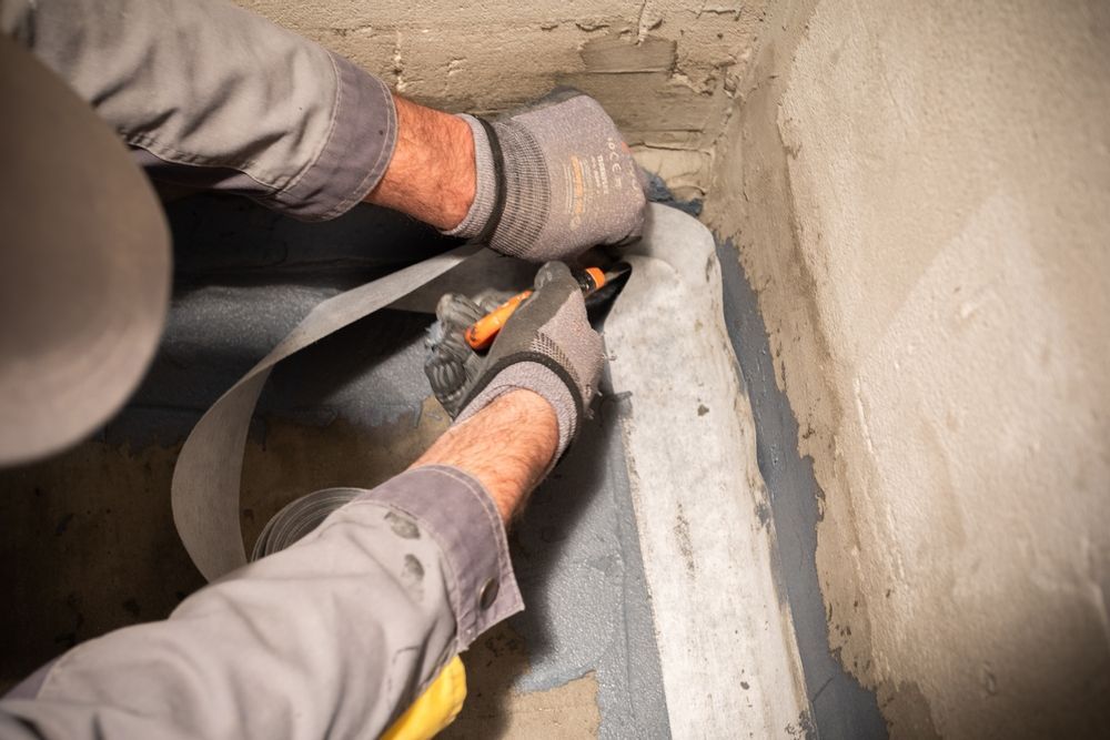 A Man is Cutting a Piece of Tape With a Pair of Scissors — Legend Waterproofing In Nords Wharf, NSW