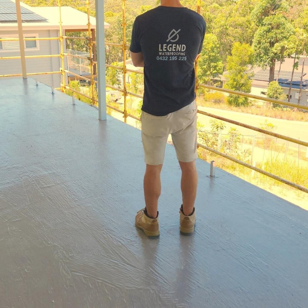 A Man Wearing a Legend T-shirt is Standing on a Balcony — Legend Waterproofing In Nords Wharf, NSW